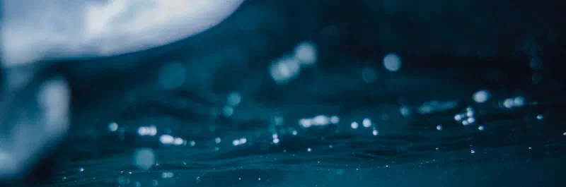 Blurred dark blue water surface with light reflections